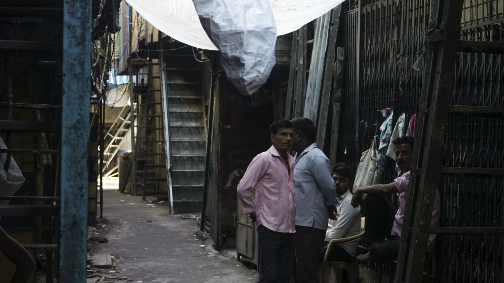 Muži v uliciach slumu Dharavi, jeden z najväčších slumov sveta.